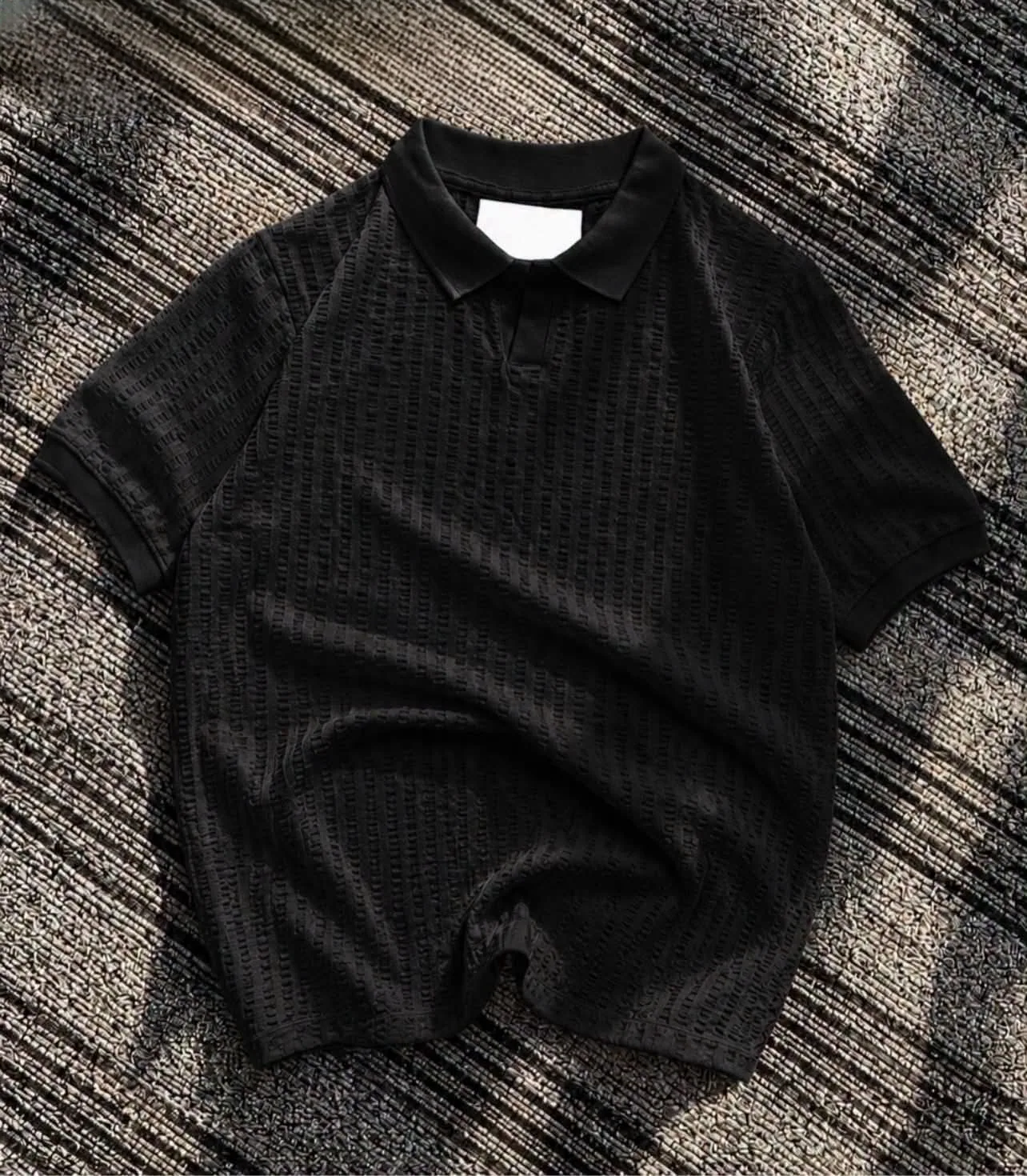 Textured black knit polo flat lay